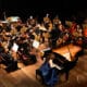 A Academia Jovem Concertante chega a Vitória em 24 de agosto com um concerto gratuito no Sesc Glória, reunindo 25 jovens músicos de todo o país para interpretar obras de Villa-Lobos, Bach, Mozart, Ernani Aguiar, Monique Aragão e Hércules Gomes. Foto: Nanah D Luize