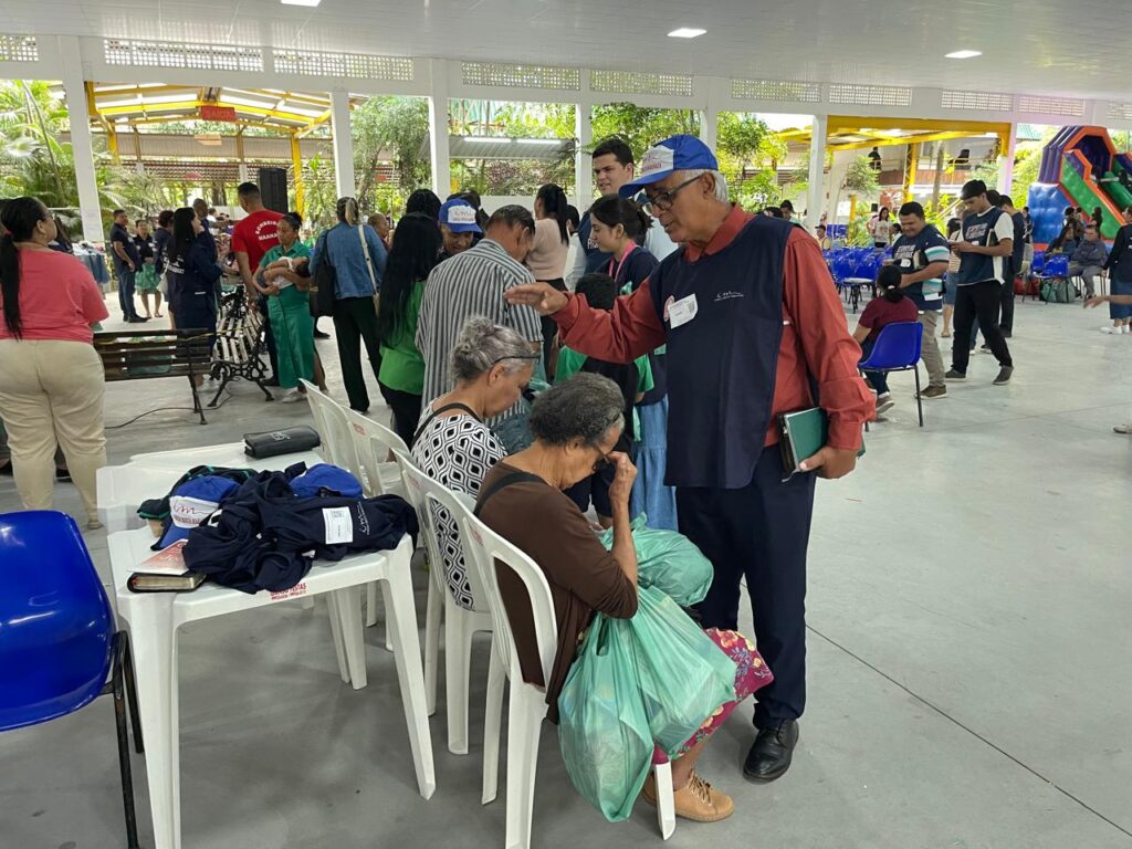 Voluntário ora com idosas durante atendimento espiritual na ação social da Igreja Cristã Maranata, em Cariacica